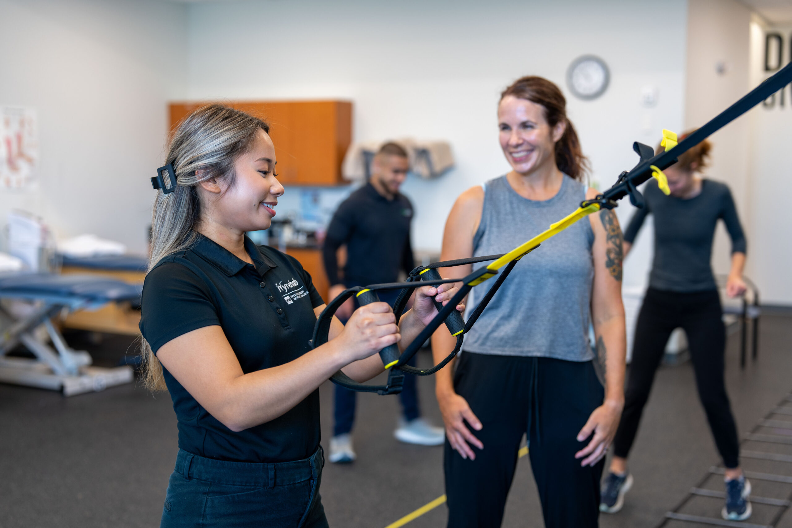 Clinician assisting a patient with a suspension trainer exercise during a physical capacity assessment