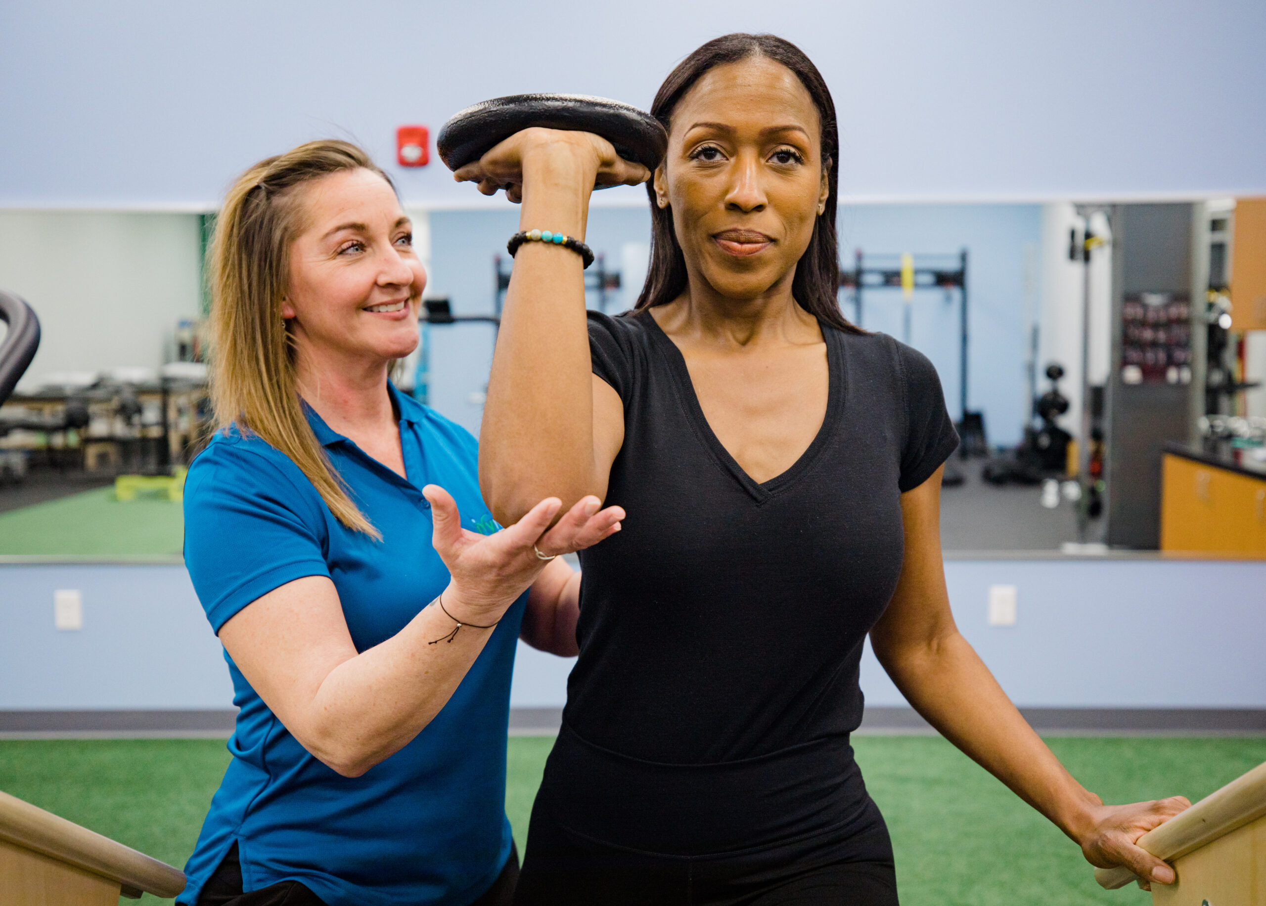 Clinician measuring a patient's shoulder mobility while she holds a kettlebell overhead