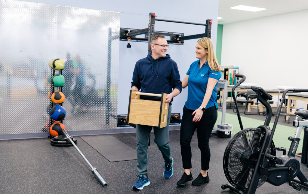Clinician observing a patient carrying a weighted box during a functional capacity evaluation