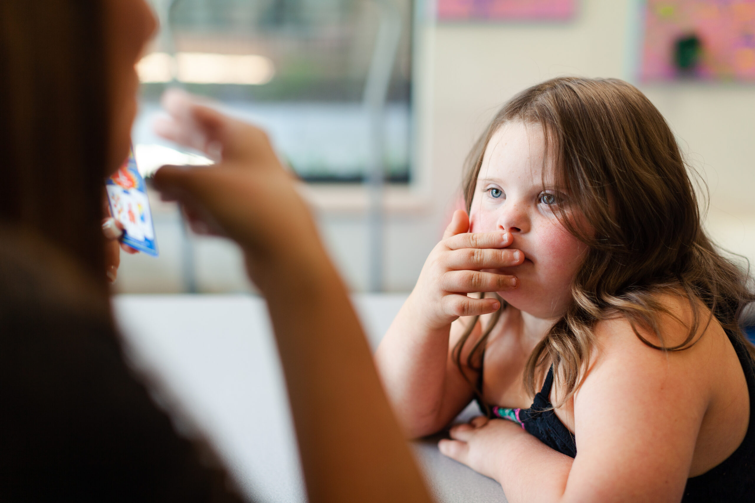 Young girl listening attentively to an adult during a pediatric therapy session