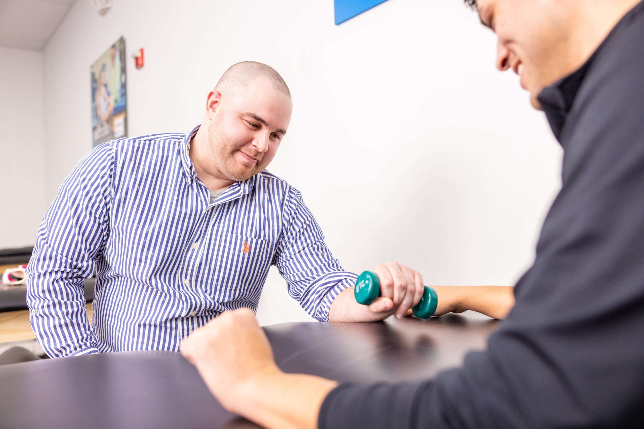 Clinician assessing an employee's wrist strength with a dumbbell during an ergonomic worksite evaluation