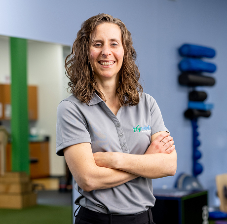 Portrait of a clinician standing arms crossed and smiling in a therapy clinic