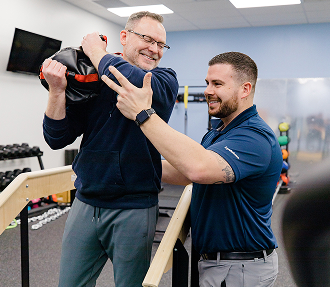 Physical therapist guiding a patient through a shoulder mobility exercise in an Ivy Health clinic