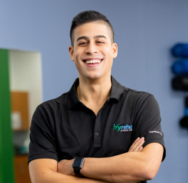 Portrait of a clinician standing arms crossed and smiling in a therapy clinic