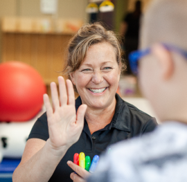 Pediatric therapist giving a young patient a high-five during a therapy session